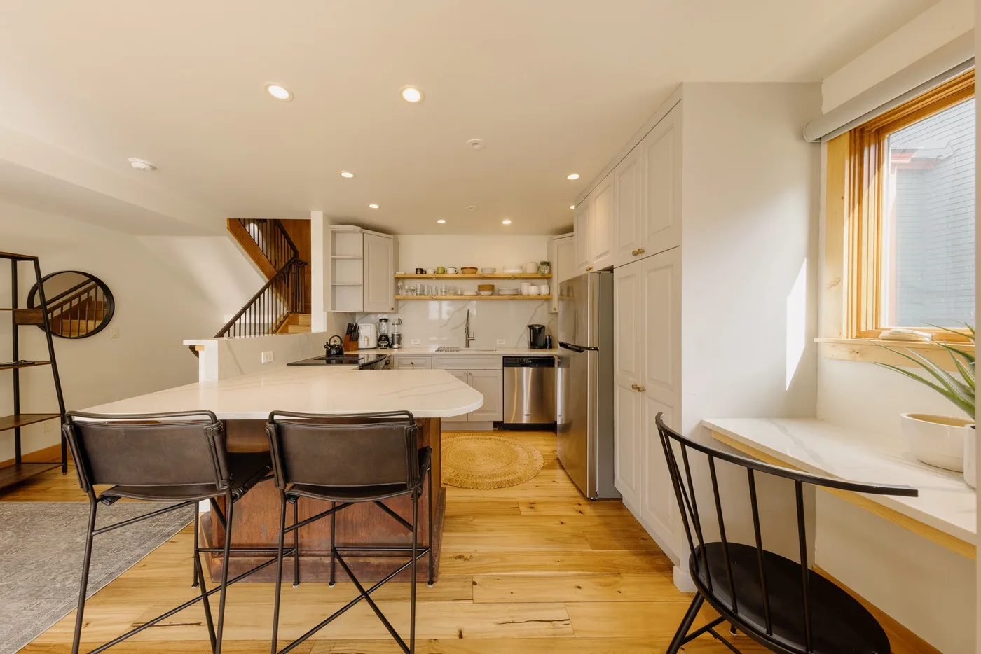Una luminosa cocina con comedor, una isla central y una ventana grande.