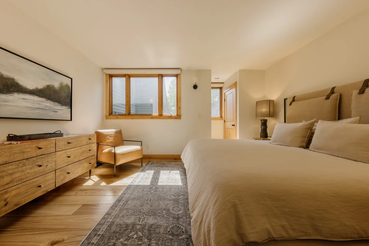Un dormitorio con una cama grande, una cómoda y una ventana con vista al agua.