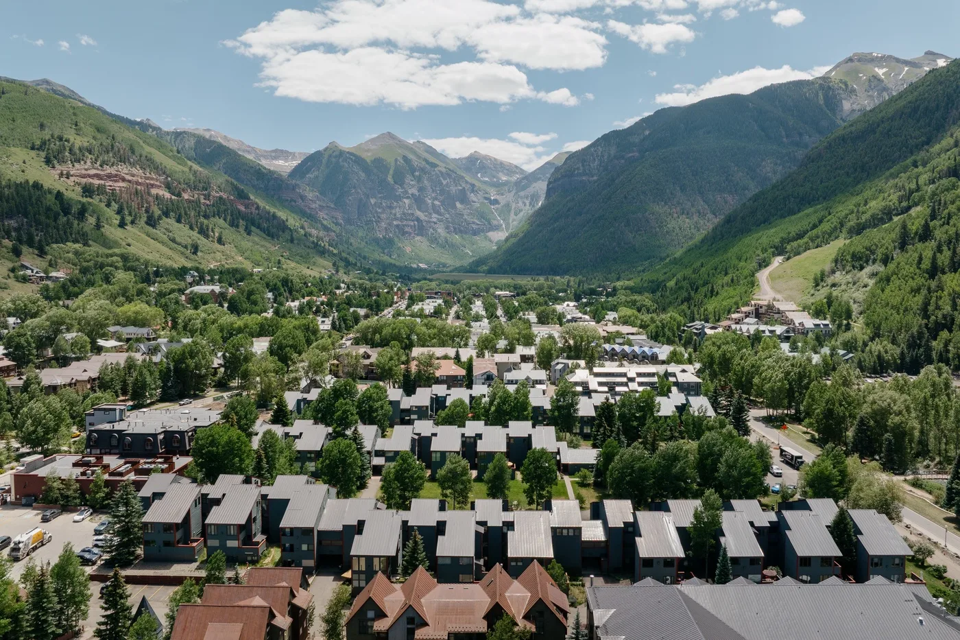 Un valle montañoso domina un pueblo con edificios y calles arboladas.