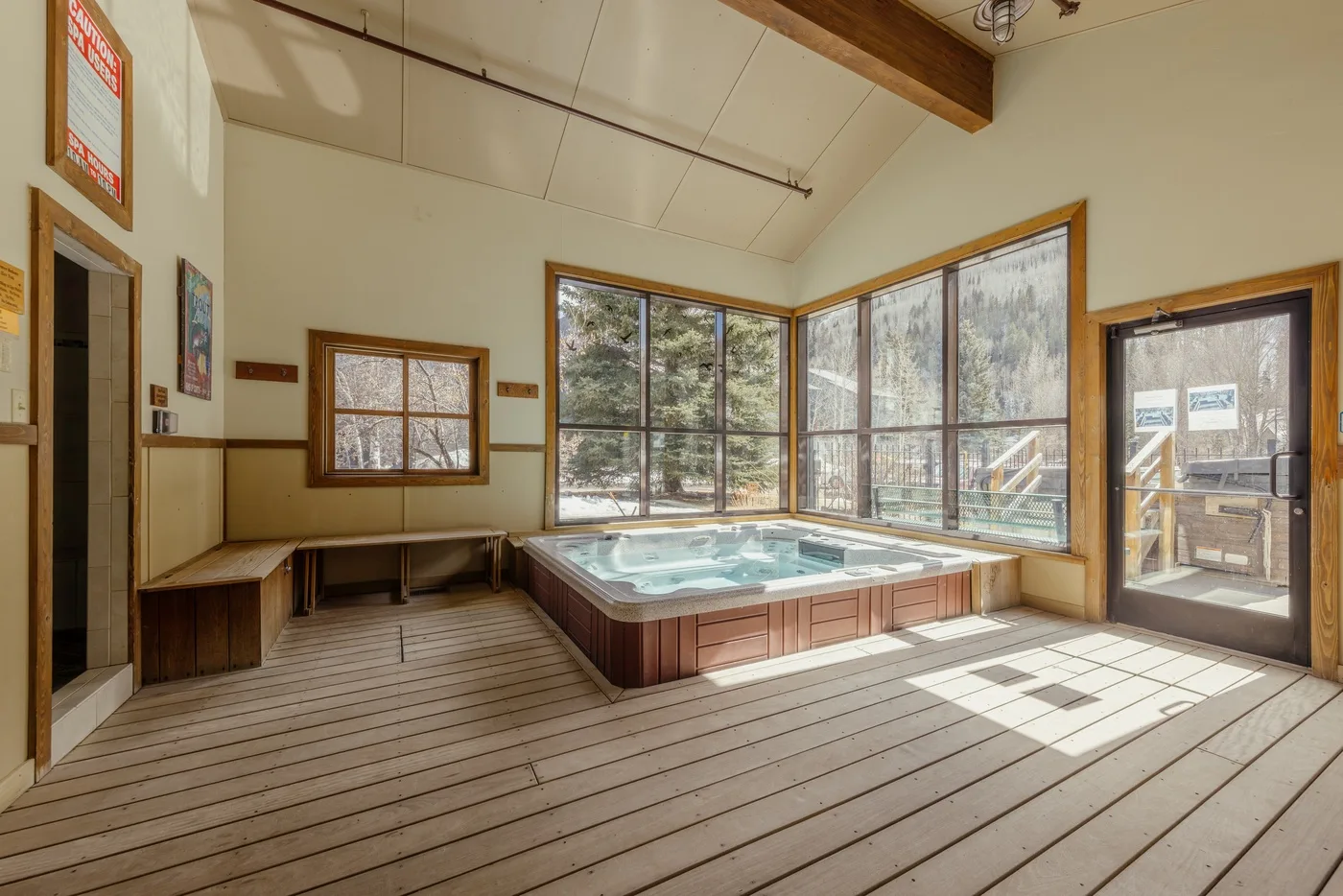Una bañera de hidromasaje interior está junto a grandes ventanas en una habitación luminosa.