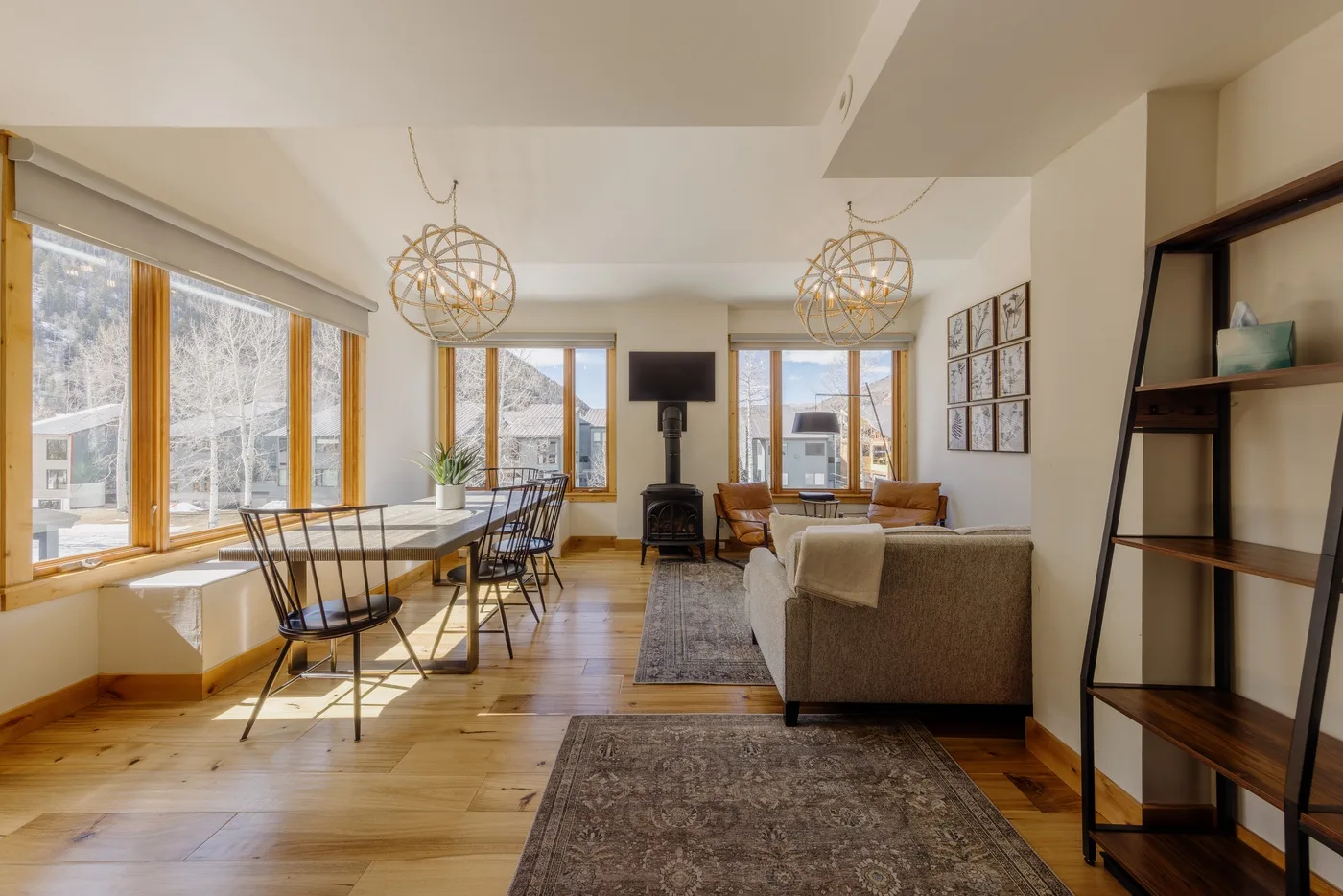Una luminosa sala de estar y comedor tiene grandes ventanas y una mesa de comedor.