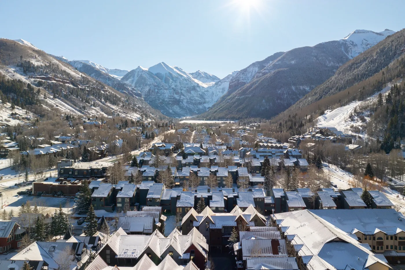 Un pueblo de montaña cubierto de nieve se extiende por un valle bajo un cielo despejado.