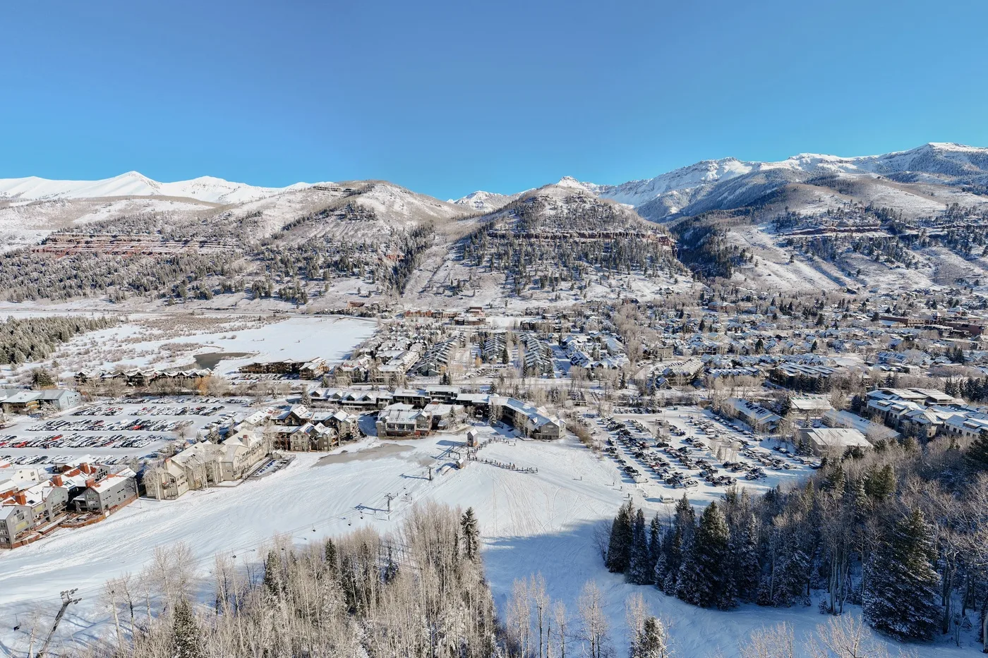 Un paisaje montañoso cubierto de nieve, con un pueblo y laderas boscosas.