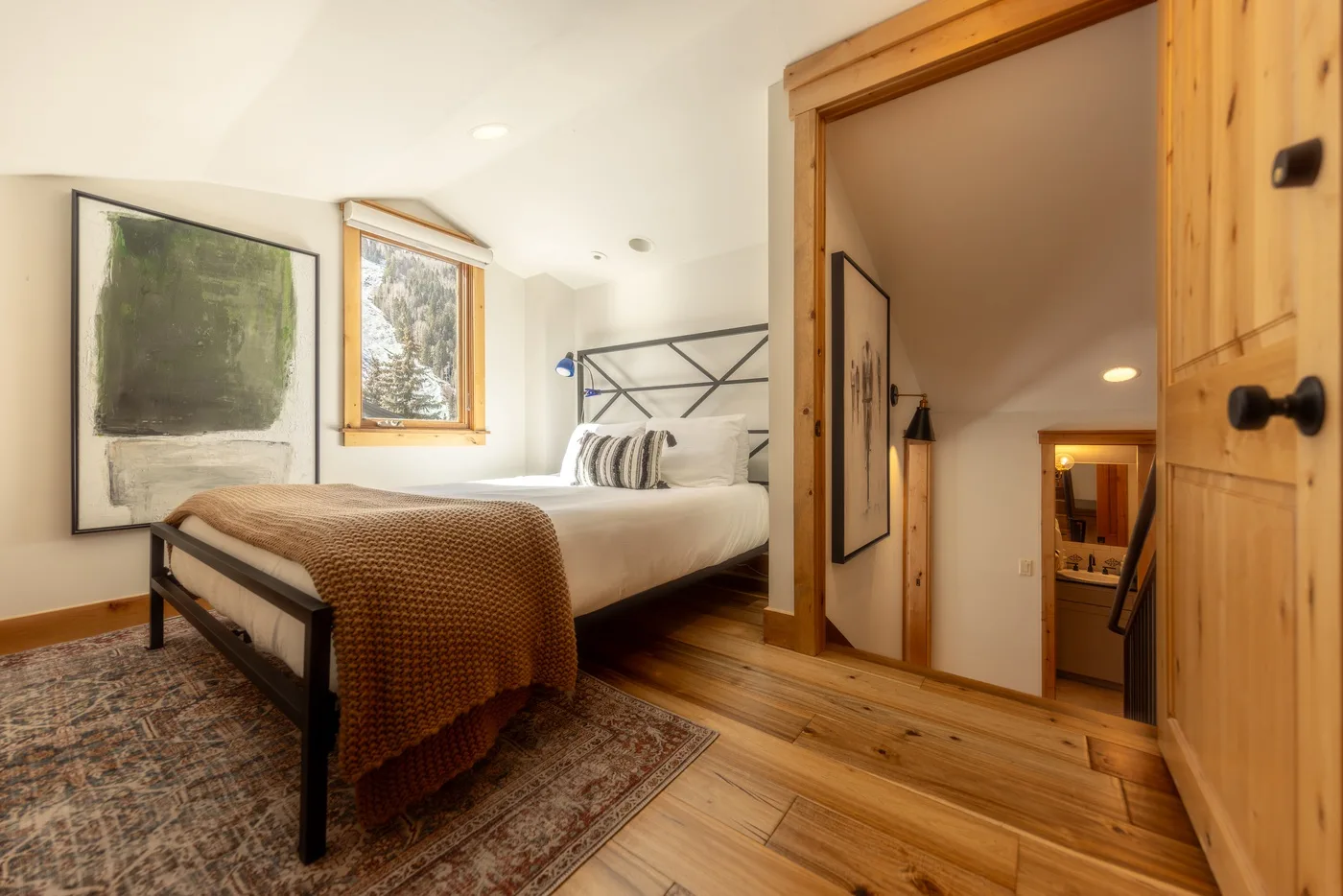 Un dormitorio con una cama, cuadros en la pared y una puerta de madera.
