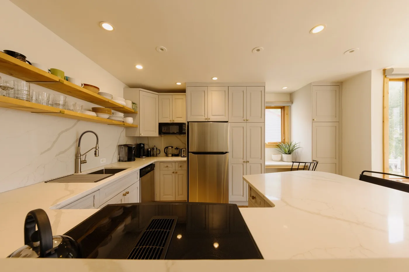 Una cocina luminosa con gabinetes claros, un refrigerador central y una isla amplia.
