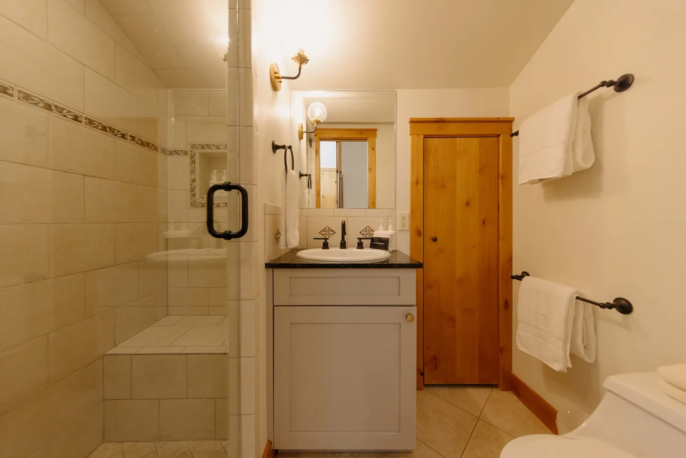 Un baño alicatado con ducha, lavabo y armario de madera.
