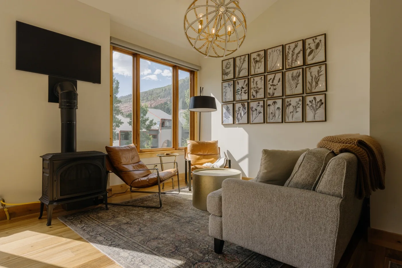Una sala de estar iluminada con asientos, una ventana amplia y una estufa de leña.