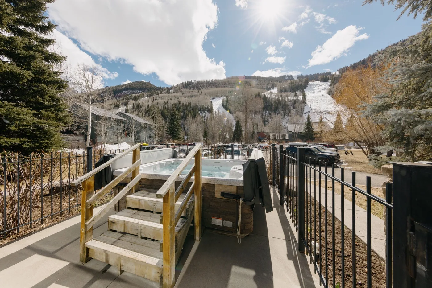 Un jacuzzi exterior está en una terraza con vistas a una pista de esquí de montaña.