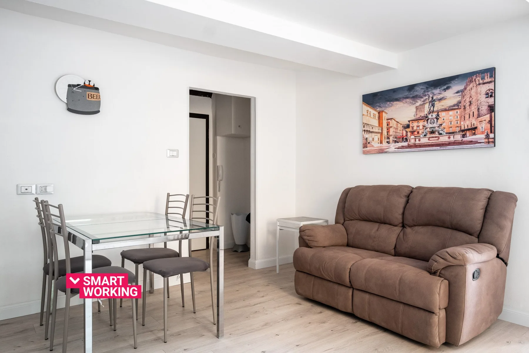 Una sala de estar con asientos marrones junto a una mesa de comedor de vidrio y sillas.