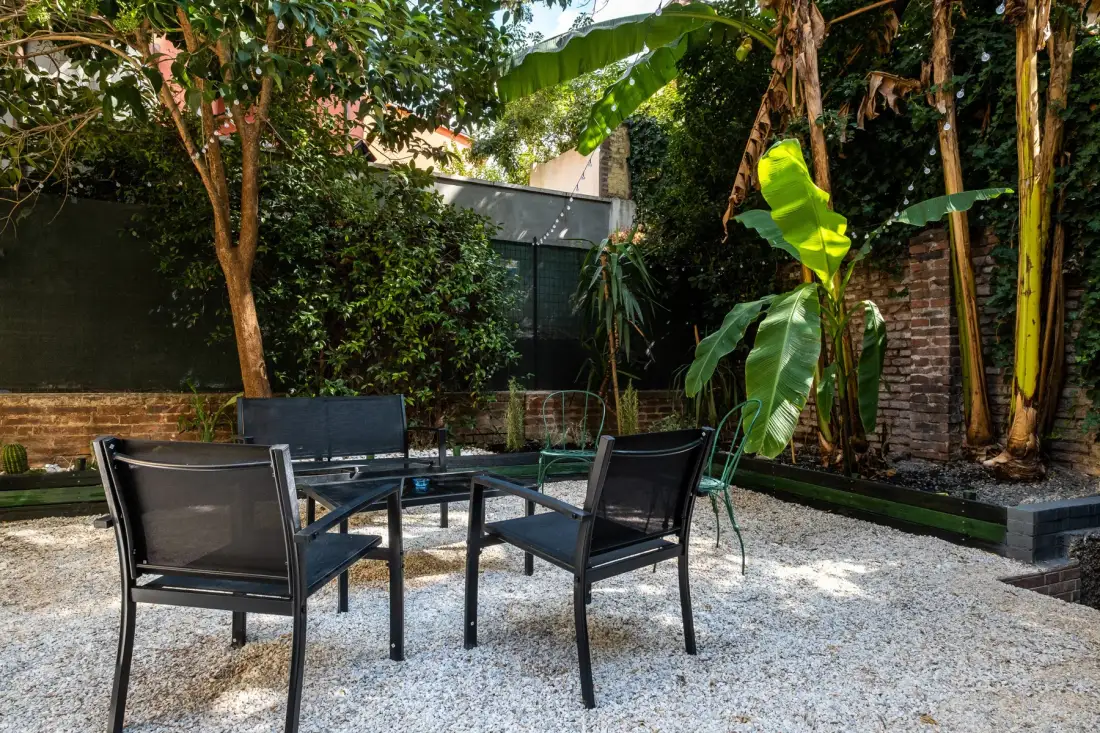 Zona de estar al aire libre con sillas y una mesa en un patio de grava.