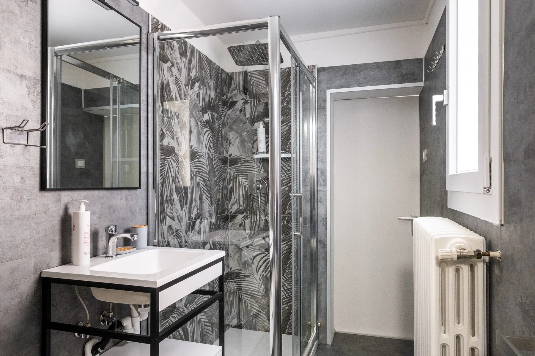 Un baño con lavabo, espejo y ducha de vidrio.
