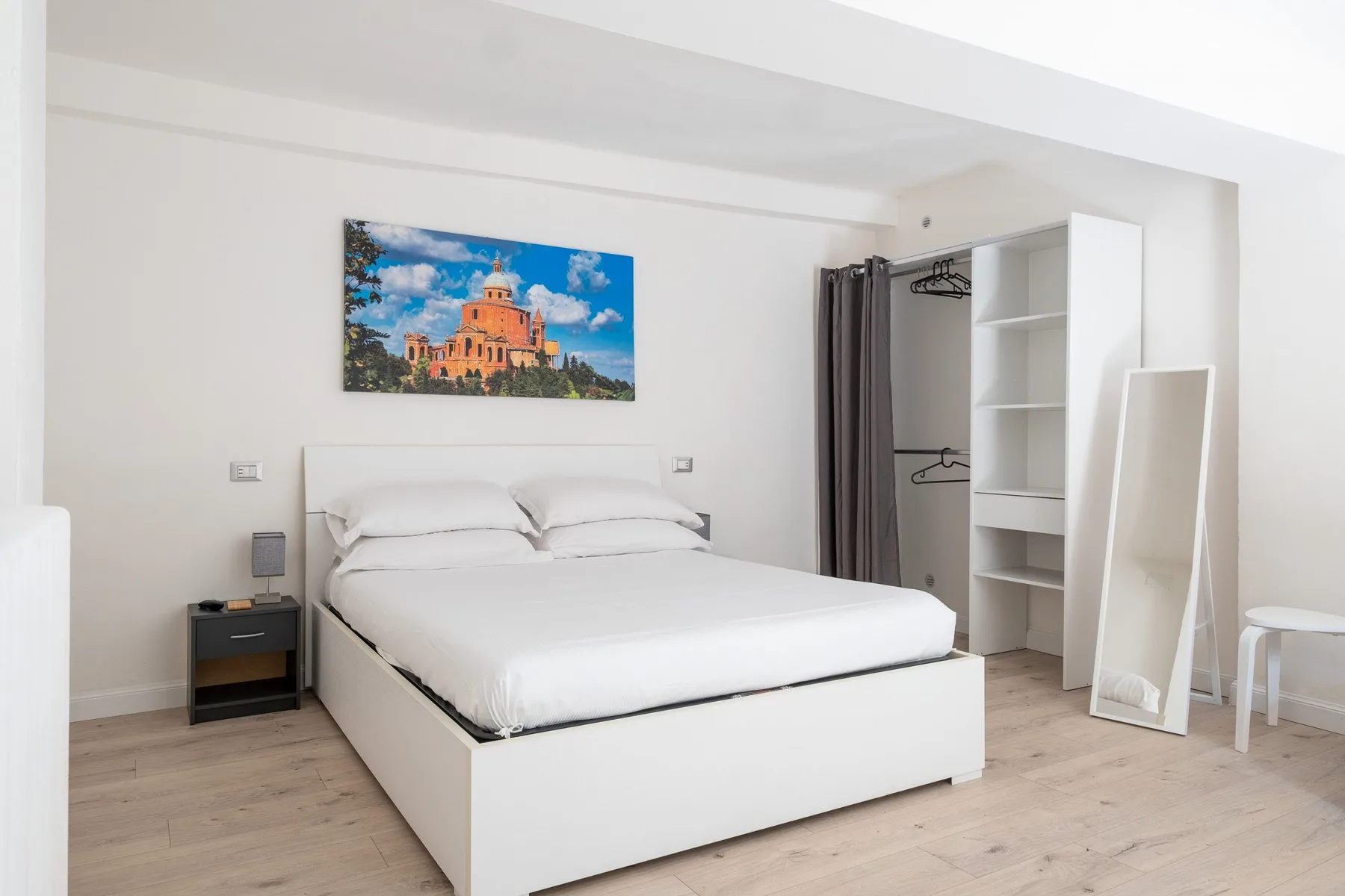 Un dormitorio luminoso con una cama bien hecha y un armario abierto.