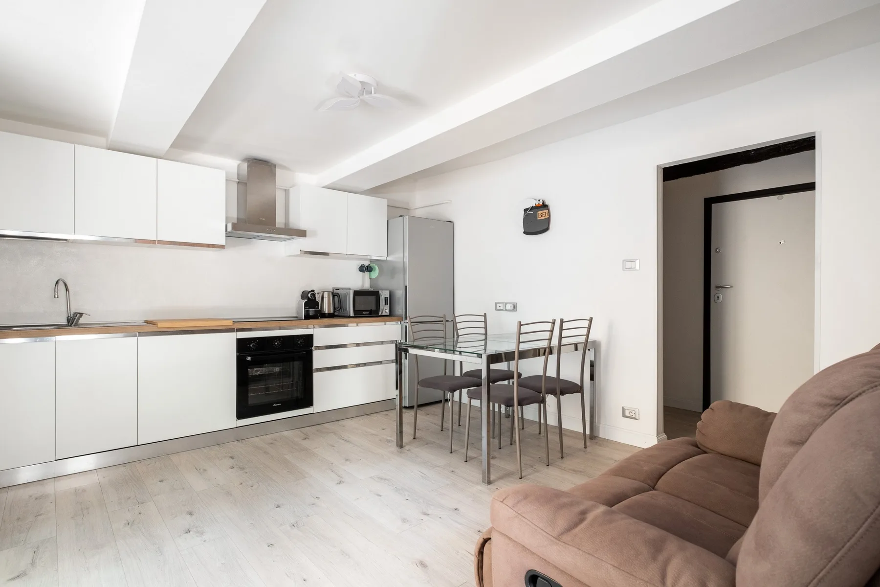 Una luminosa sala de estar de espacio abierto con cocina, mesa de comedor y asientos.