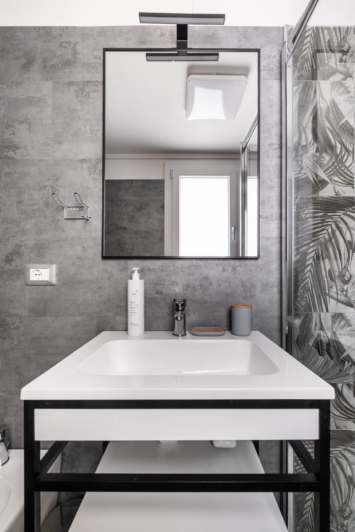 Un lavabo moderno de baño con espejo y azulejos estampados en la pared.