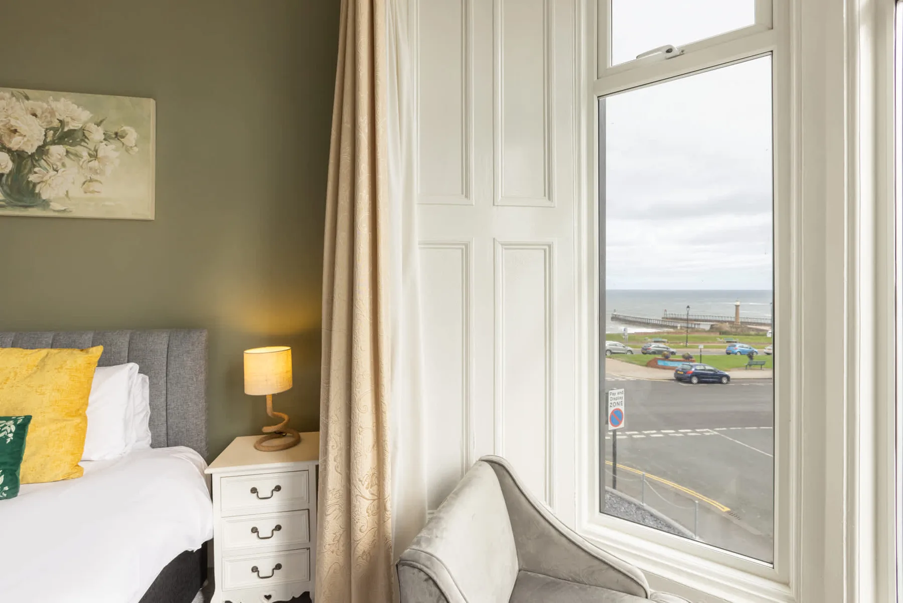 A bedroom with a bed beside a window overlooking the waterfront.