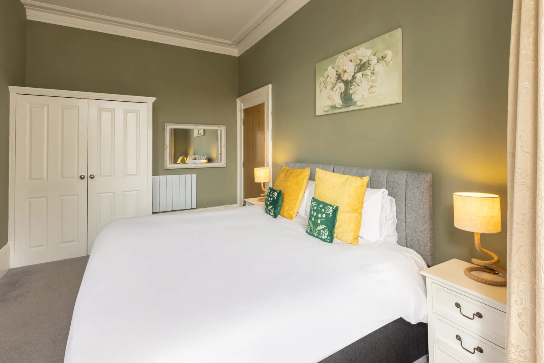 A bedroom with a large bed, colorful pillows, and bedside lamps.