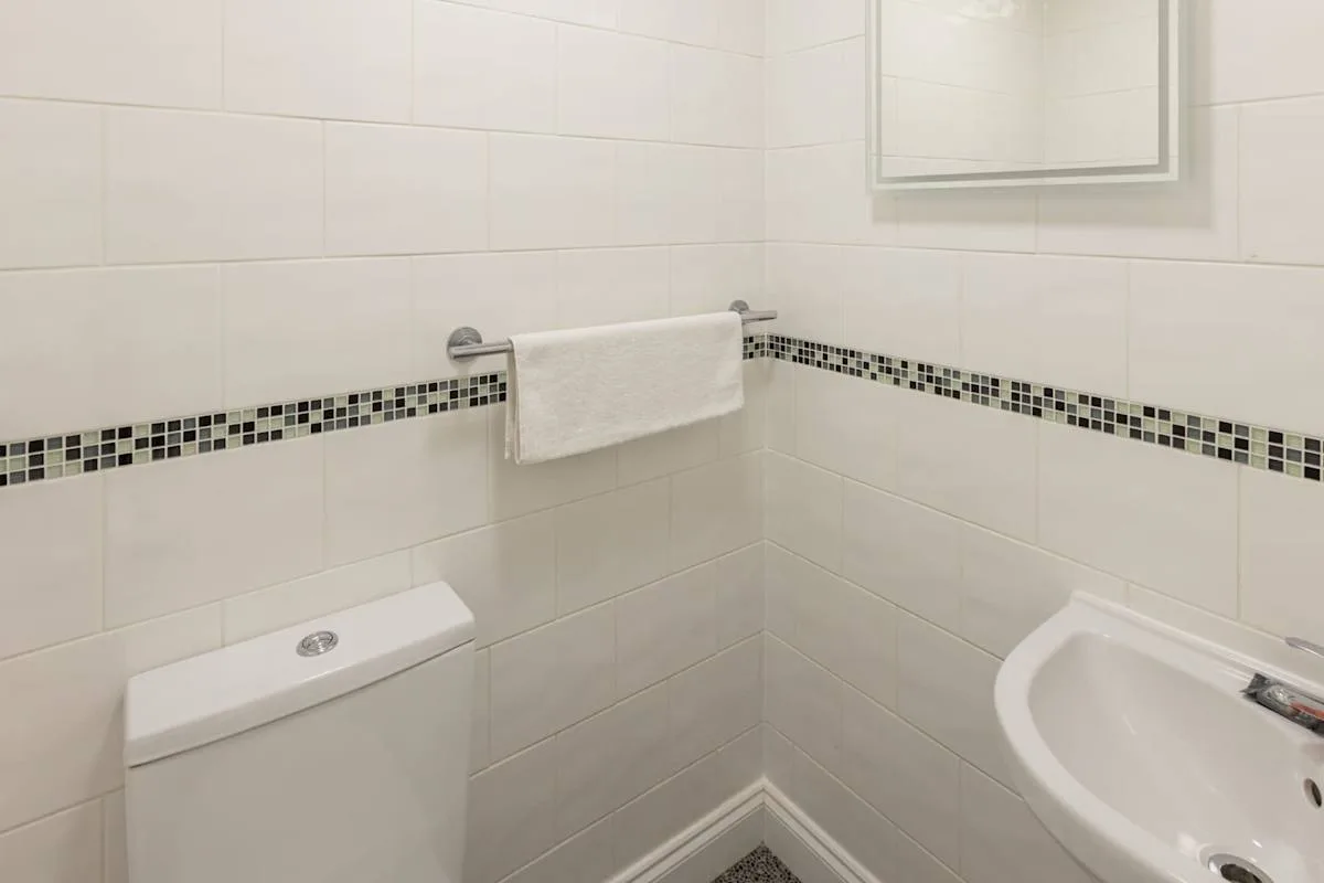 A tiled bathroom with a towel rack and sink.
