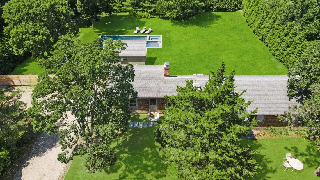Aerial view of a house surrounded by a green lawn and trees.