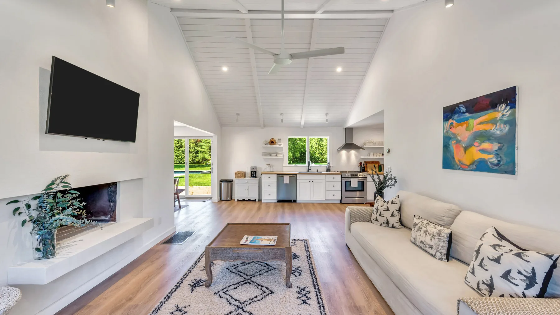A bright living room with a sofa, coffee table, and wall-mounted television.