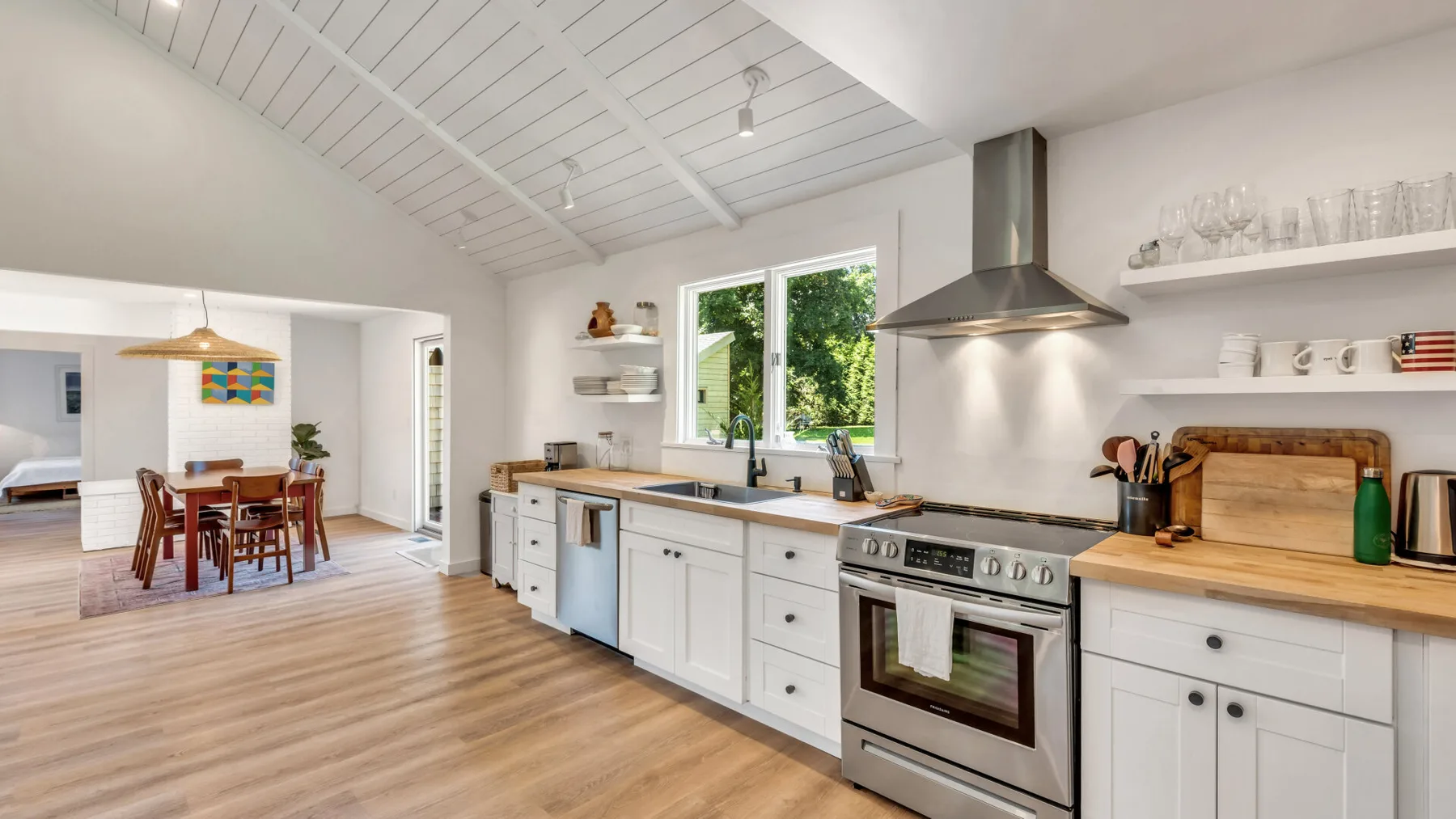A bright kitchen with white cabinets, a stove, and a large window.