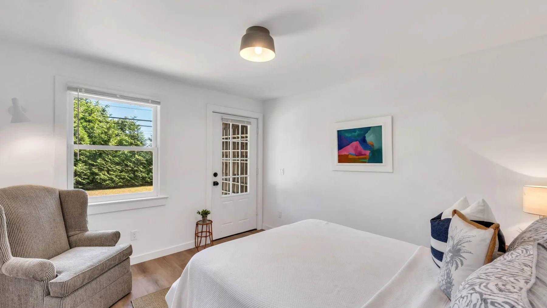 A bright bedroom with a bed, a window, and a glass-paneled door.