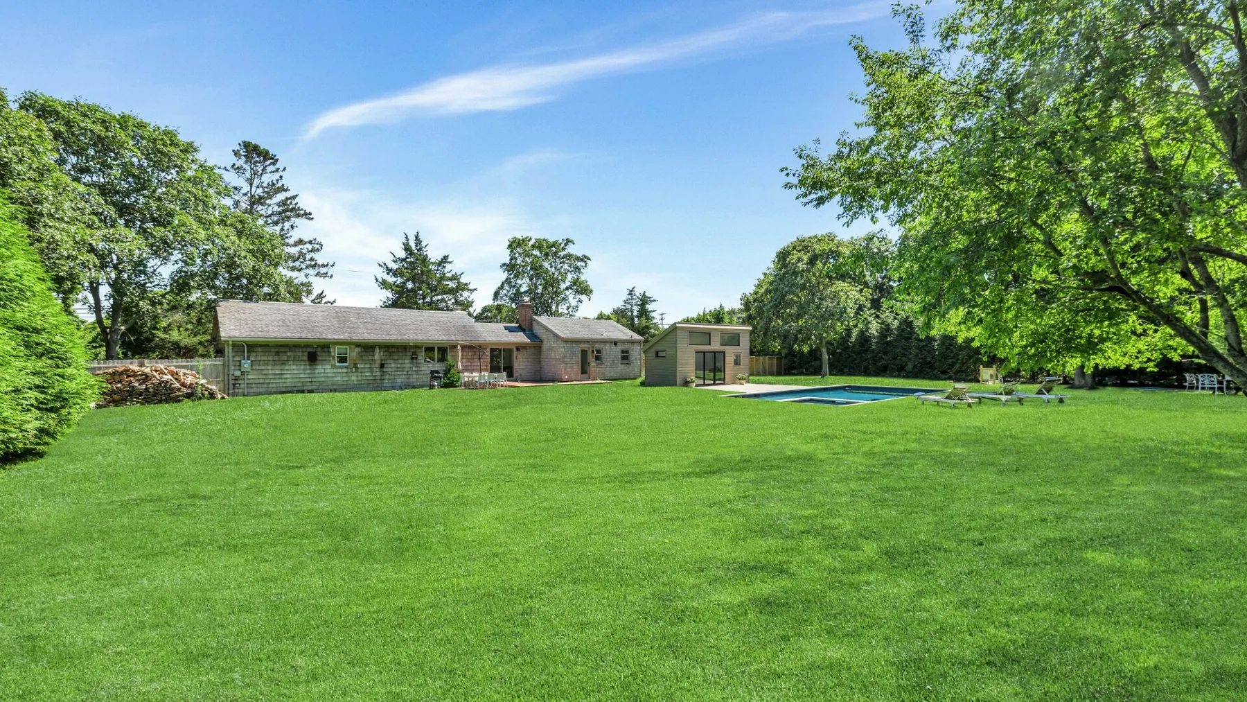 A broad green lawn with a swimming pool and low buildings in the background.