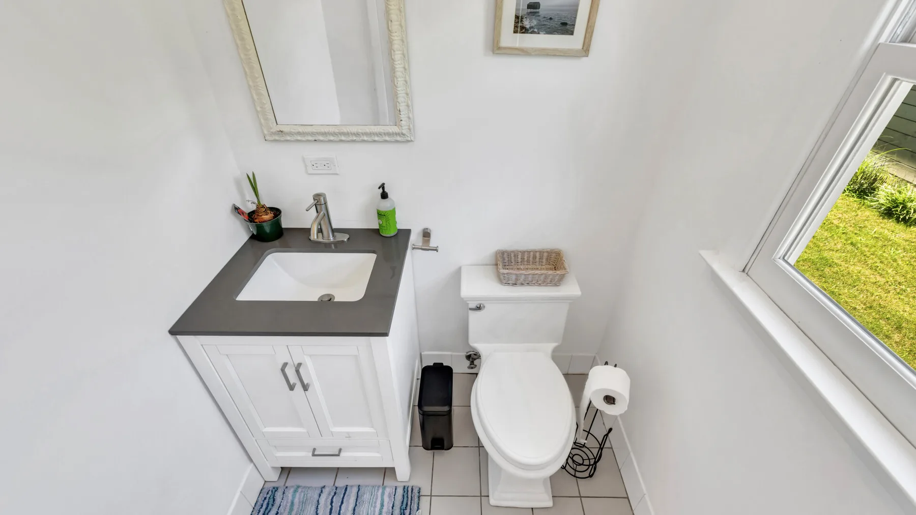 A small bathroom with a vanity, toilet, and window.