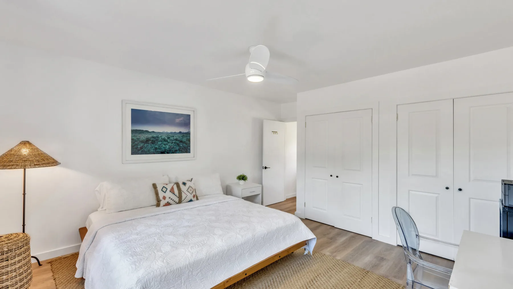 A bright bedroom with a neatly made bed and white closet doors.