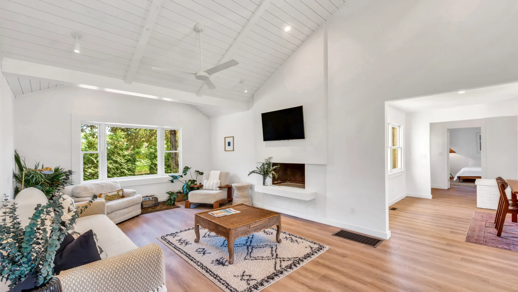 A bright living room with seating, a coffee table, and a wall-mounted television.
