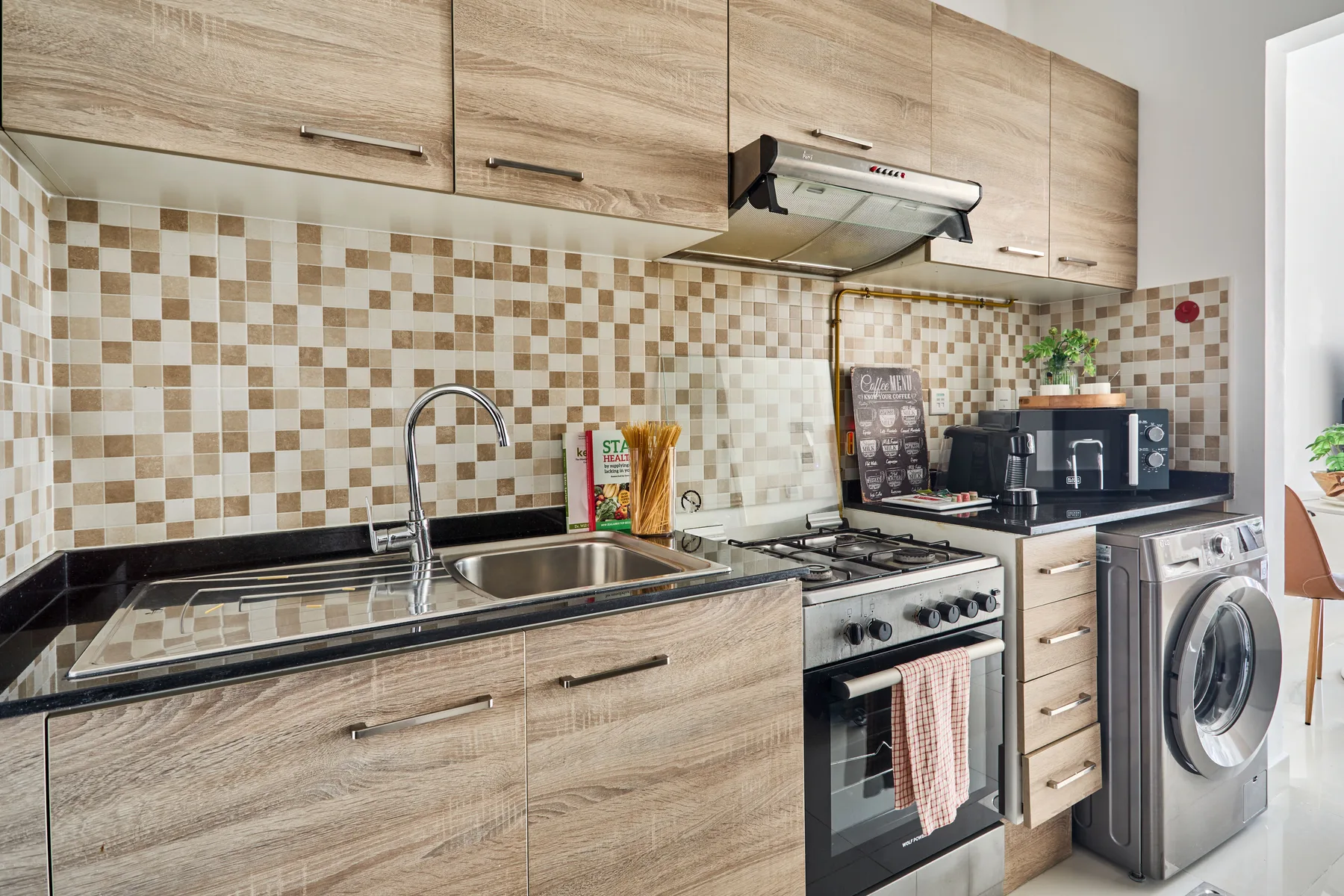Una cocina con gabinetes de tono madera, un salpicadero de azulejos y electrodomésticos de cocina.