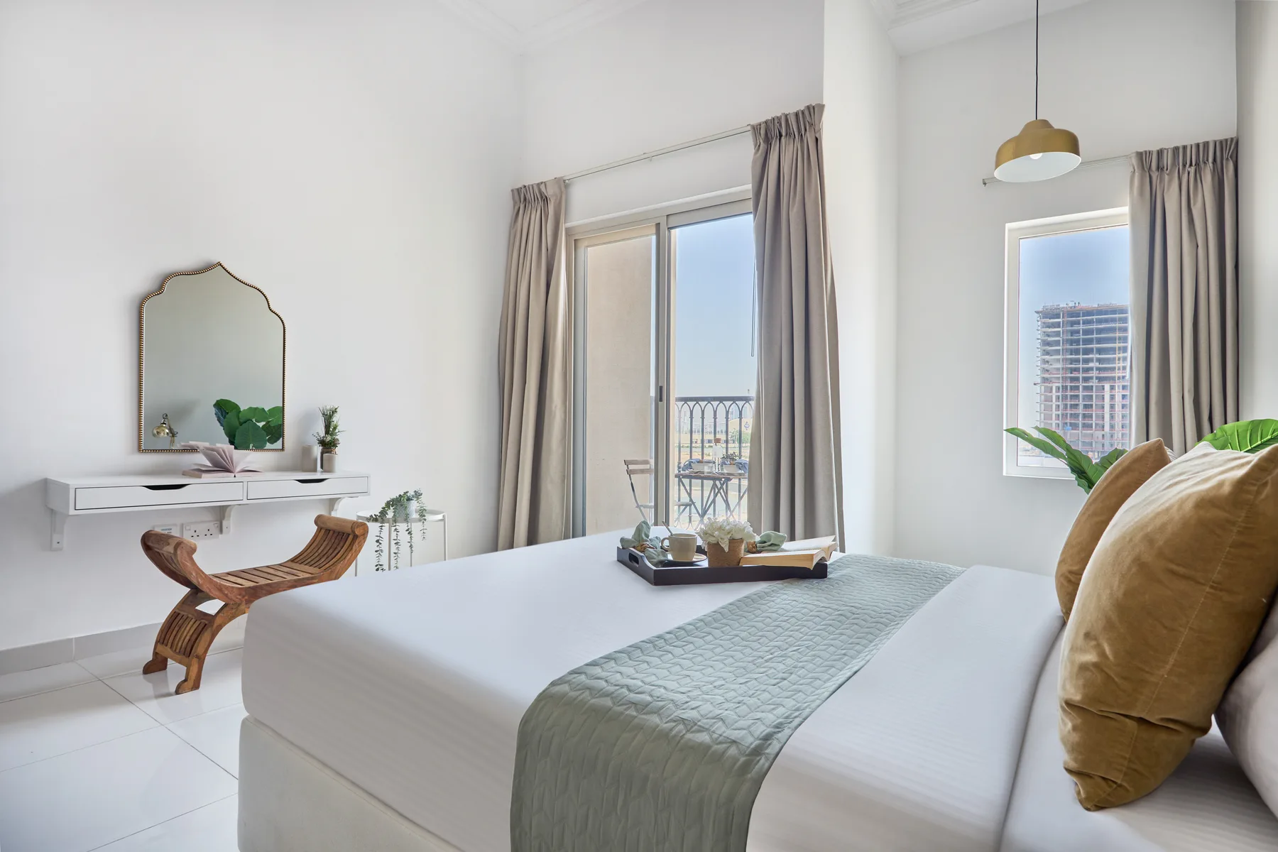 Un dormitorio luminoso con una cama bien tendida y ventanas altas.