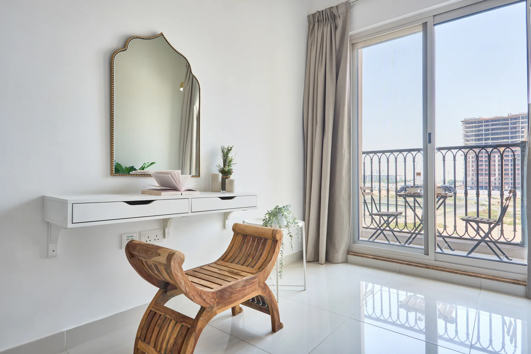 Una luminosa zona de estar con un sillón de madera junto a una ventana grande.