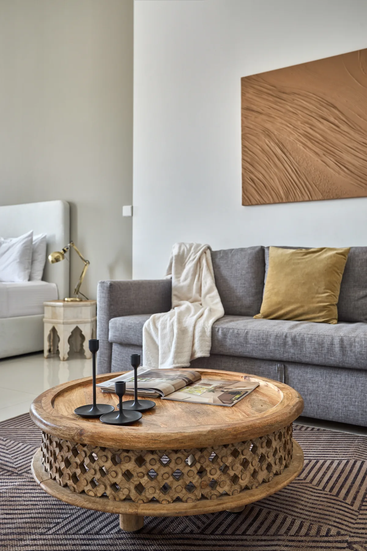 Una sala de estar con asientos grises y una mesa de centro redonda de madera.