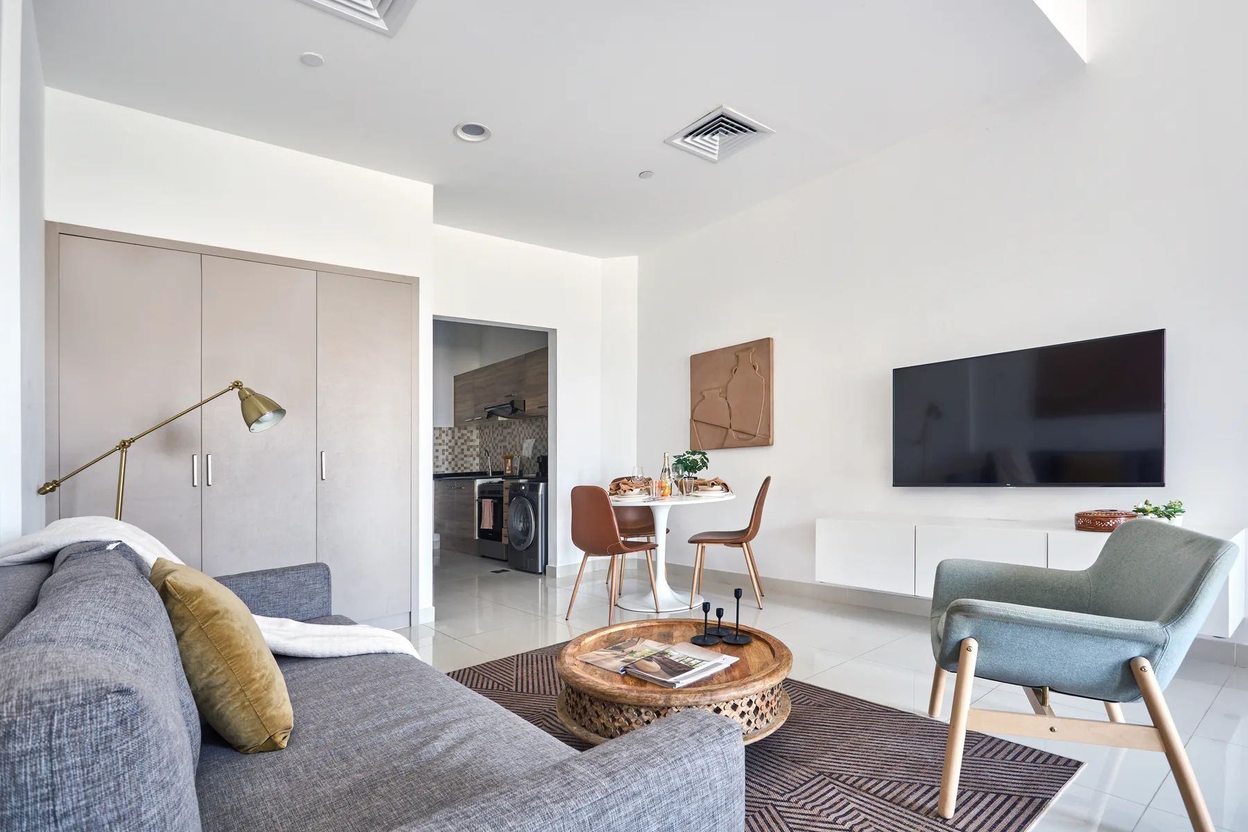 A bright living room with seating, a television, and a dining area.