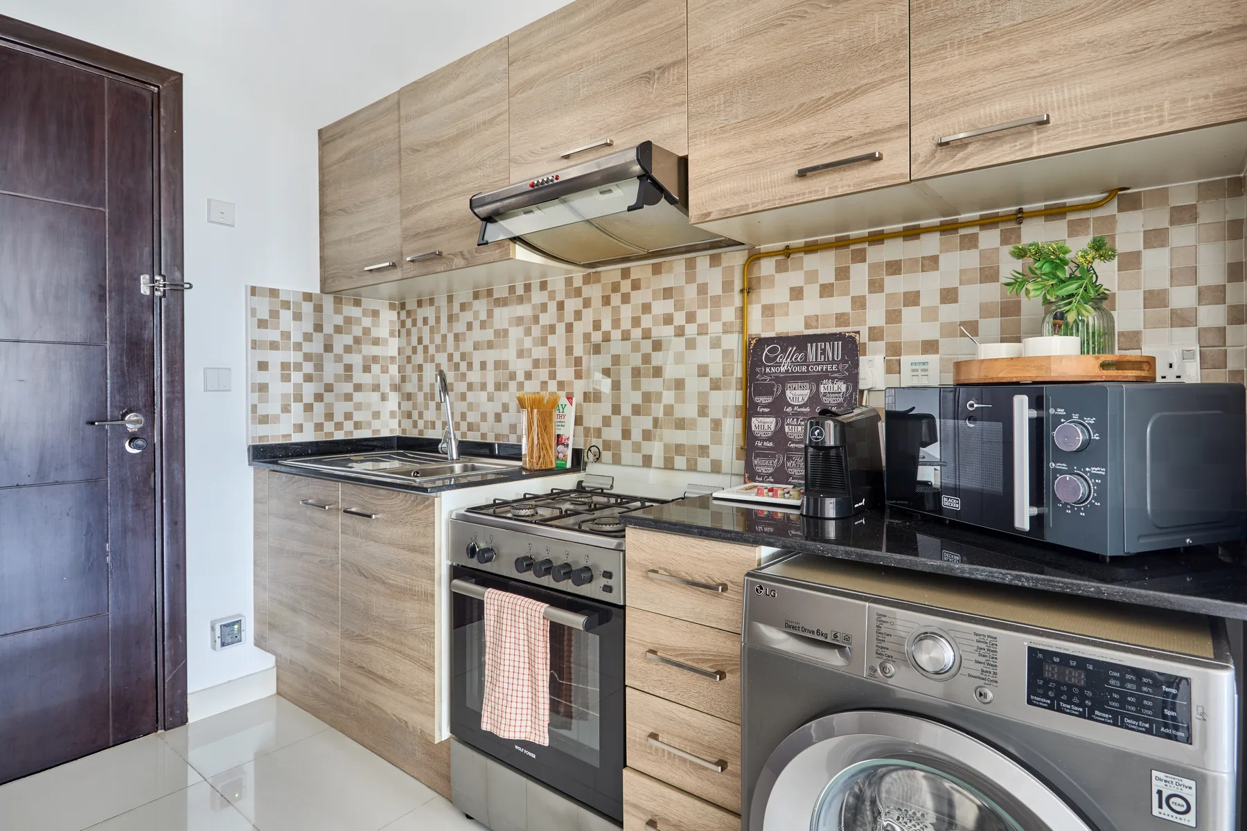 Una cocina con gabinetes de acabado madera, una estufa y electrodomésticos sobre la encimera.
