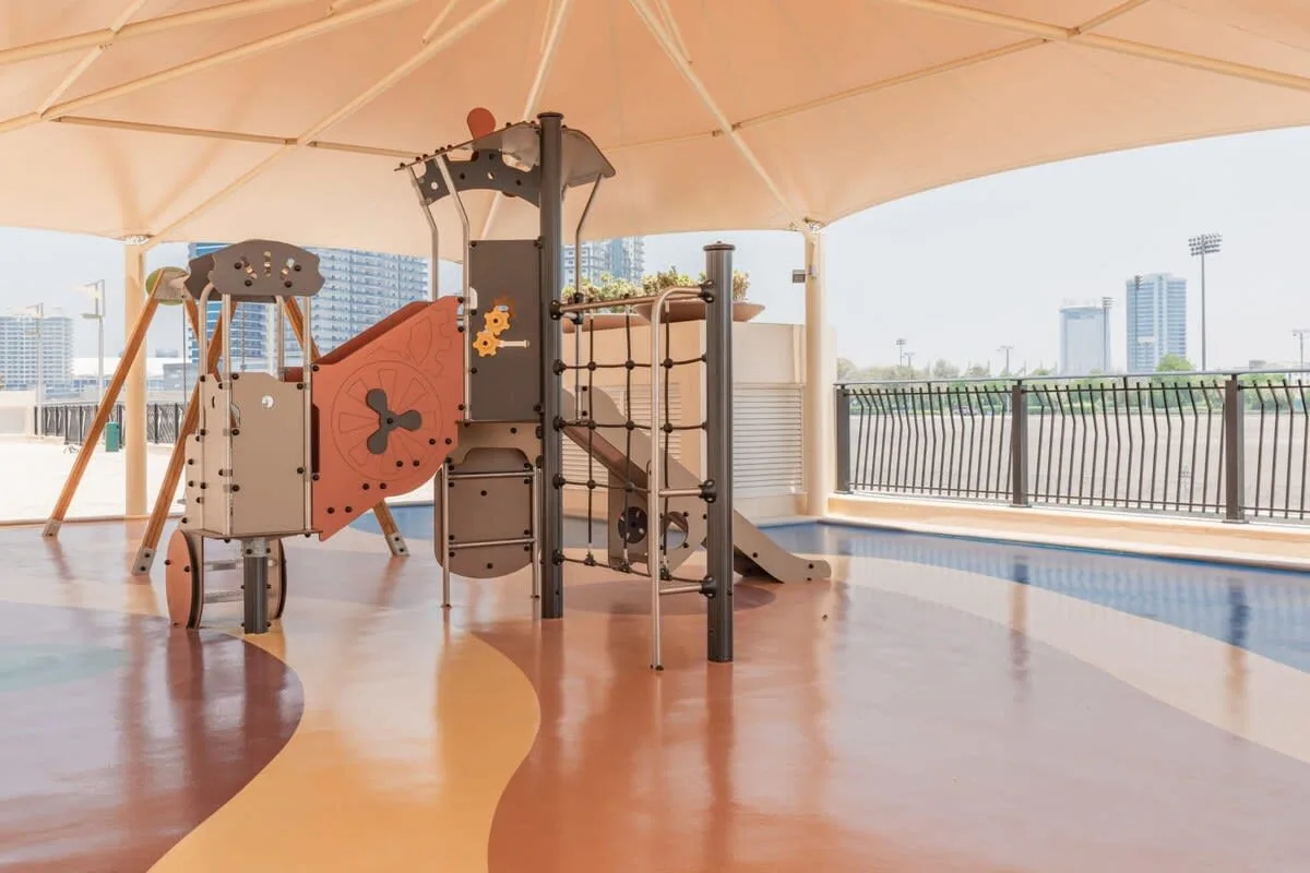 Una estructura de juegos está bajo una cubierta junto a una piscina al aire libre.