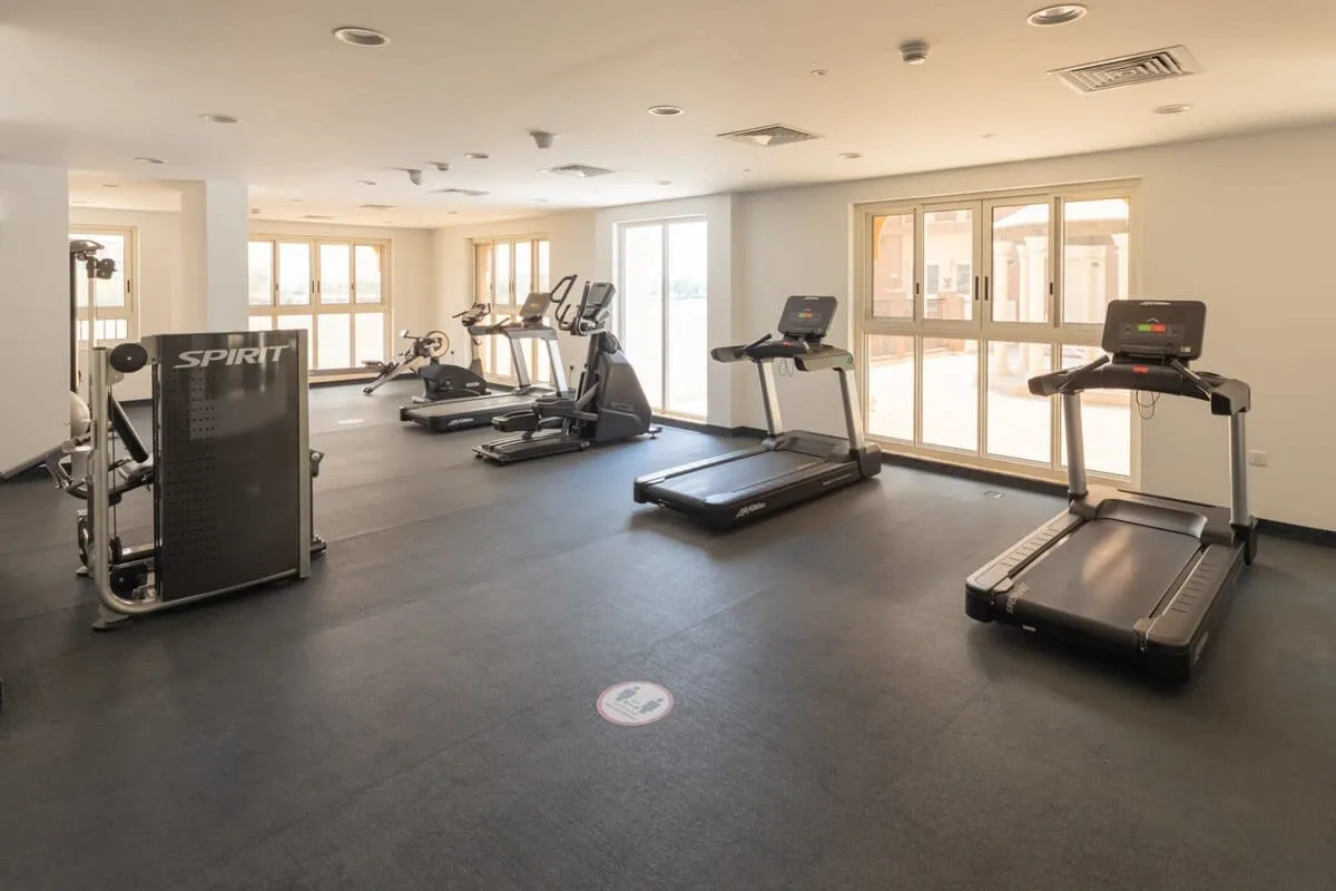 Una sala de ejercicios con cintas de correr y equipos distribuidos por el espacio.
