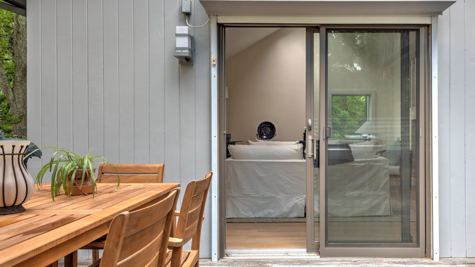 Un dormitorio da a una terraza de madera con mesa y sillas.