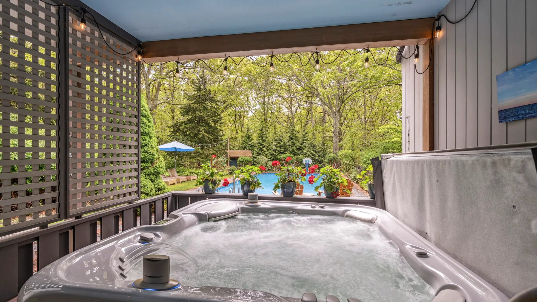 Un jacuzzi exterior cubierto tiene vistas a un jardín con árboles y flores.