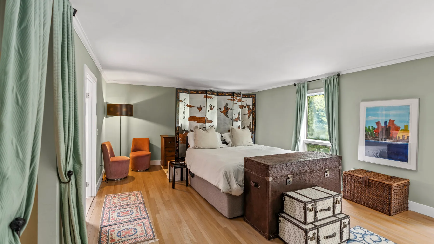 Un dormitorio con una cama grande, sillas coloridas y obras enmarcadas.