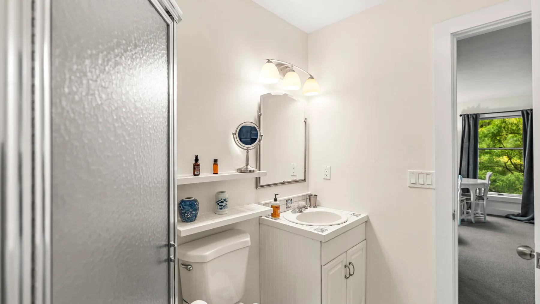 Un baño con lavabo, inodoro y ducha con mampara de vidrio.