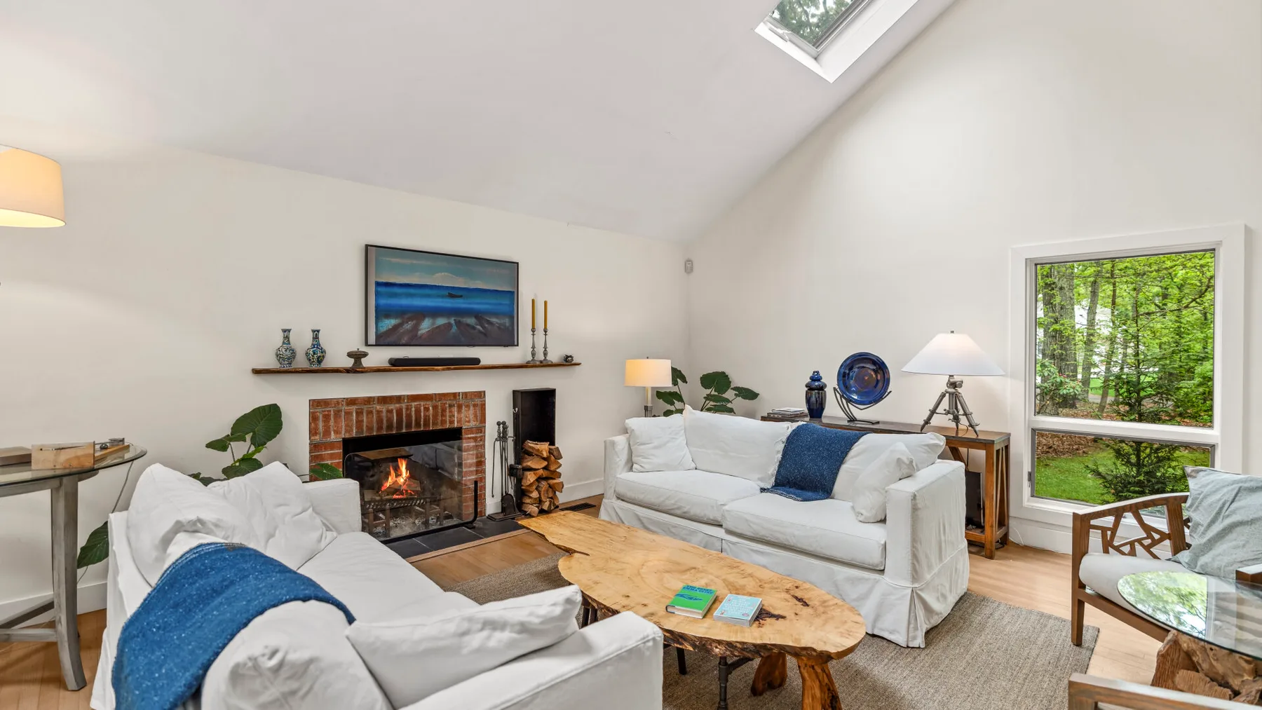 Una sala luminosa tiene una chimenea, asientos y una claraboya.