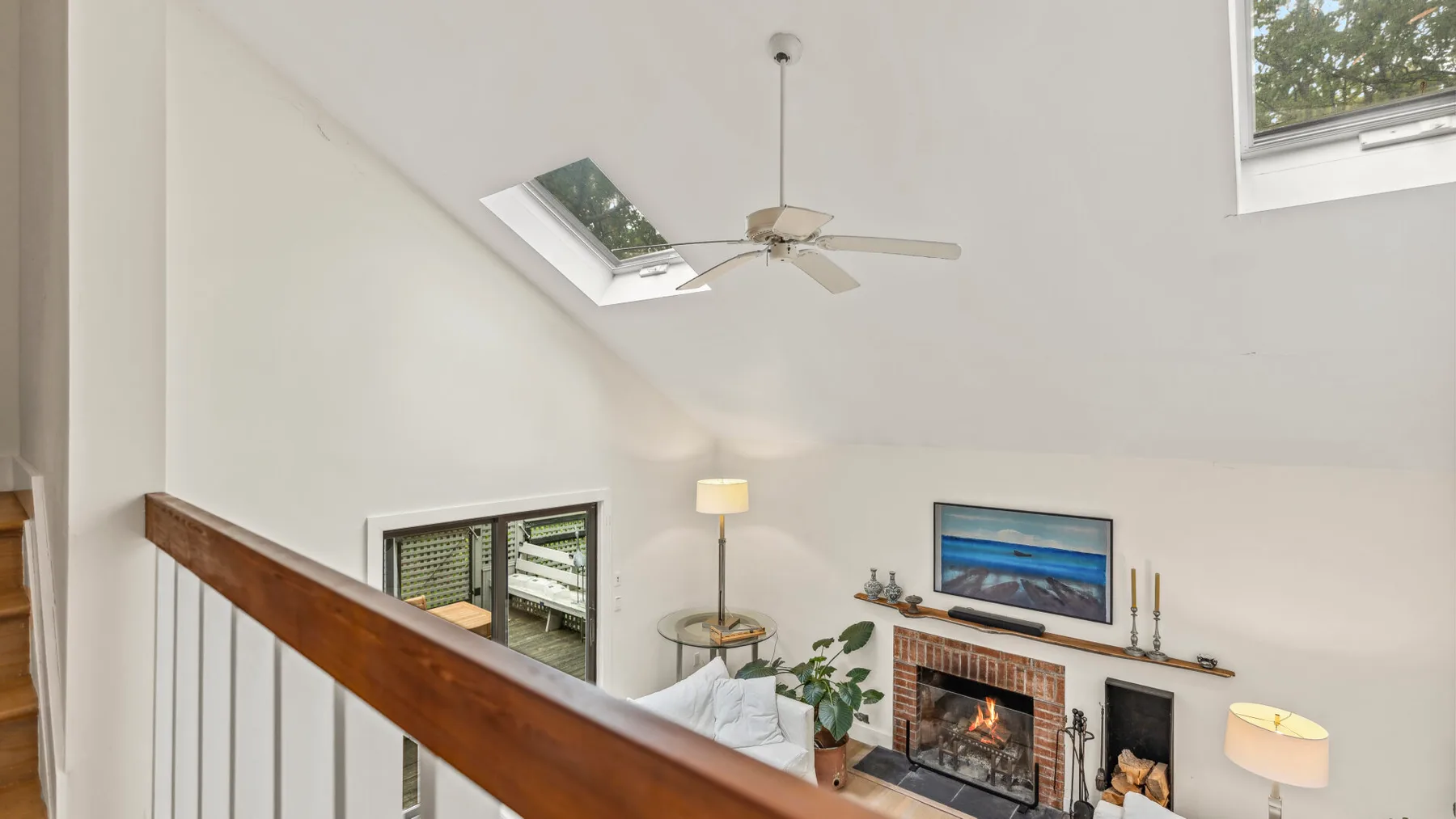 Una sala luminosa con chimenea, asientos y techo inclinado.