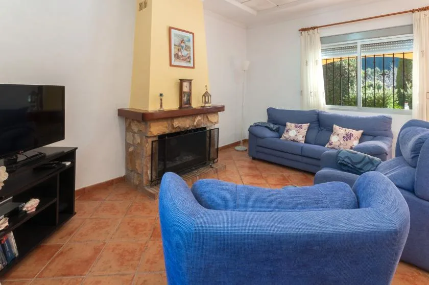 A living room with blue seating, a fireplace, and a television.