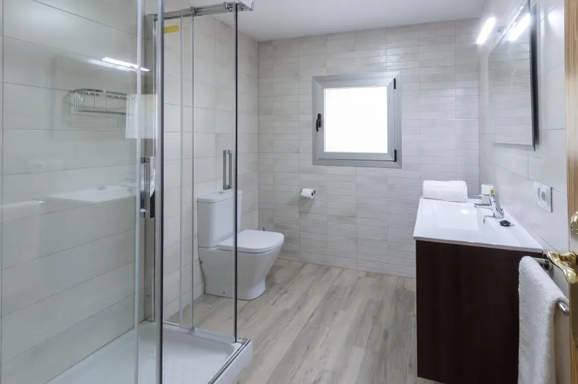 A bright tiled bathroom with a glass shower and vanity.