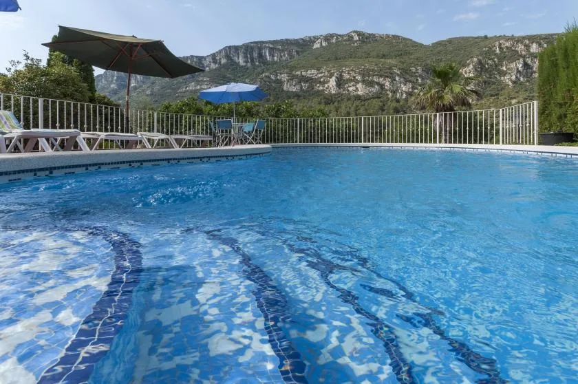 An outdoor swimming pool overlooks green, rocky mountains.