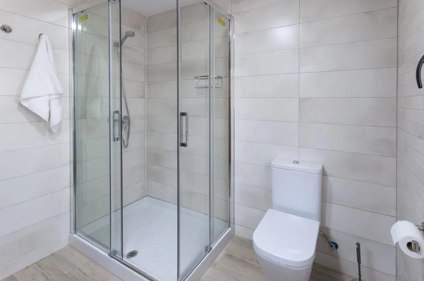 A tiled bathroom with a glass shower and toilet.