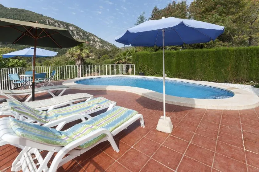 An outdoor swimming pool beside lounge seating and umbrellas.
