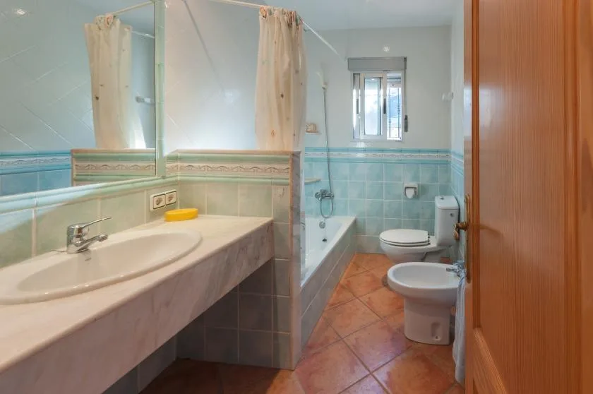 A bathroom with a long sink counter, bathtub, and toilet.