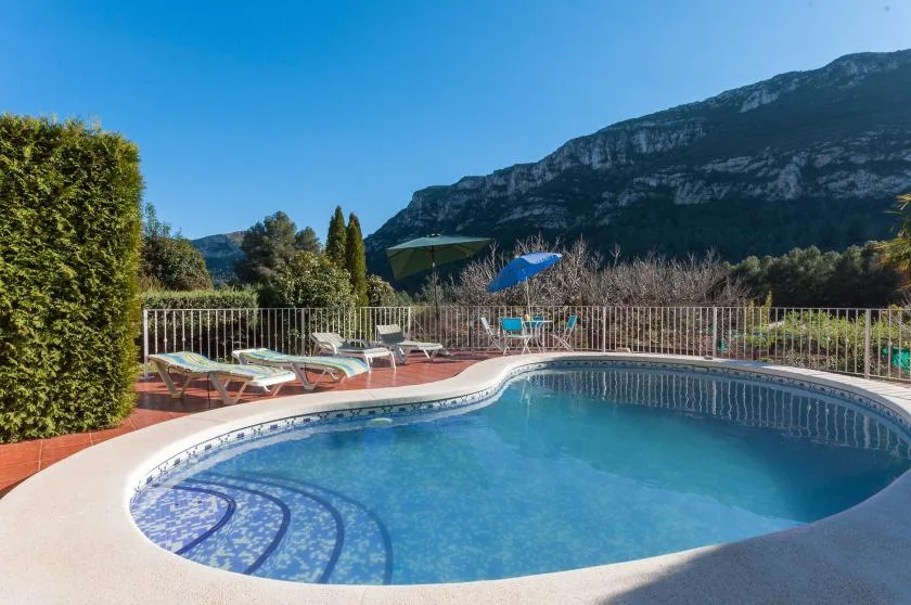 A curved outdoor swimming pool sits beside a sun terrace with loungers.